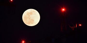 A building crane of the business district of Porta Garibaldi is pictured against the Super Snow Moon on February 19, 2019 in Milan\u002E (Photo by Marco BERTORELLO / AFP)   superluna astronomia