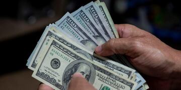 AME5421\u002E CARACAS (VENEZUELA), 31/07/2020\u002E- Un hombre cuenta un fajo de billetes de dólar el 30 de julio de 2020, en Caracas (Venezuela)\u002E La imparable inflación que vive Venezuela ha llevado a la inevitable dolarización de facto, a la que el presidente Nicolás Maduro se ha rendido después de años de críticas y rechazo a la divisa estadounidense, y defensa a ultranza del bolívar -moneda nacional sobreviviente a decenas de batallas-, cuyo valor se encuentra bajo mínimos\u002E EFE/ Rayner Peña R