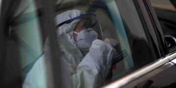 A Covid-19 tester reflects in a car window during the talk with a car driver before the driver takes a smear himself in a car testing station in Erkheim, southern Germany, on November 4, 2020, amid the new coronavirus COVID-19 pandemic\u002E (Photo by Christof STACHE / AFP)