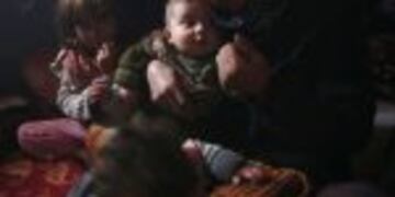 The mother (R) of Rasha al-Qassem (UNSEEN), who recently fled rebel-held Aleppo into the Syrian government held side, holds her grandchildren as the family reunites in their make-shift home in Syria's second city, on December 1, 2016.nRasha was among tens