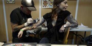 A tattooist works on a woman's arm during the first day of the second