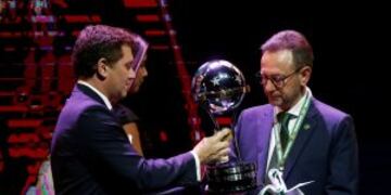 Conmebol President Alejandro Dominguez, left, presents the Sudamericana Championship trophy to Brazil's Chapecoense President Plinio de Nes during a Copa Libertadores soccer championship drawing ceremony, in Luque, Paraguay, Wednesday, Dec. 21, 2016. The first round of 58th edition of this championship will start on Jan. 23, 2017. (AP Photo/Jorge Saenz)