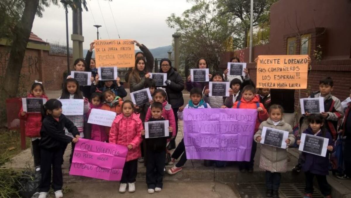 Compañeros de los hijos de Maria Laura Dominguez con carteles en la puerta de escuela pidiendo que los niños