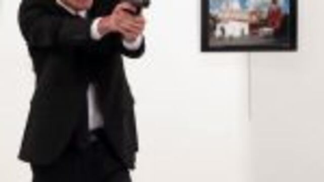 An unnamed gunman points his gun, after shooting the Russian Ambassador to Turkey, Andrei Karlov, at a photo gallery in Ankara, Turkey, Monday, Dec. 19, 2016. A gunman in a suit and tie shouted slogans about Syria's civil war after he killed Russia's amba