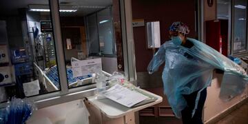 A doctor puts a protective gown as she gets ready to check patients at the Intensive Care Unit of the Barros Luco Hospital in Santiago, on July 22, 2020 amid the COVID-19 novel coronavirus pandemic\u002E (Photo by Martin BERNETTI / AFP)