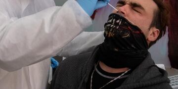 A health worker collects a nasal swab sample from a passenger to be tested for COVID-19 before he is allowed to board a ferry to Buenos Aires, at Argentinian ferry service company Buquebus' terminal in the port of Montevideo, on July 10, 2020\u002E - Technicians of the Technological Laboratory of Uruguay (LATU) set up a floating laboratory on a ferryboat of Buquebus -the only liner linking the capitals- after the polemic entry to Uruguay of two Argentinian citizens infected with COVID-19 in June\u002E The Uruguayan government of President Luis Lacalle Pou requires since Monday that travellers from abroad have a negative test for the new coronavirus done within 72 hours before the trip and another one seven days after, since flights from Europe were resumed\u002E (Photo by Pablo PORCIUNCULA / AFP)