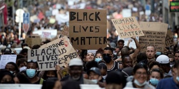 FILE - In this June 6, 2020, file photo, a protester looks up at a sign that reads \