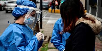 Argentinian dentist Agostina Guerra (L), who graduated from the University of Buenos Aires (UBA), is pictured working as a volunteer to detect cases of the COVID-19 coronavirus, in La Boca neighborhood, Buenos Aires, on August 3, 2020\u002E - A group of volunteers of the University of Buenos Aires (UBA) is dedicated to look for coronavirus-infected people\u002E (Photo by RONALDO SCHEMIDT / AFP) hisopado casos del dia hisopados test testeos en un colectivo detectar