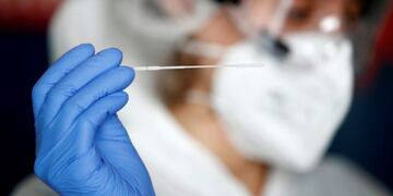 A health worker, wearing a protective suit and a face mask, prepares to administer a nasal swab to a patient at a testing site for the coronavirus disease (COVID-19) in Nantes, France, October 6, 2020\u002E REUTERS/Stephane Mahe