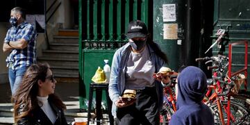 A waitress serves customers at a table placed outside a bar at San Telmo neighborhood, in Buenos Aires, on Septiembre 5, 2020, amid the new coronavirus pandemic\u002E - Restaurants and bars reopened in the city of Buenos Aires after six months of lockdown with tables placed in open-air spaces\u002E (Photo by ALEJANDRO PAGNI / AFP)