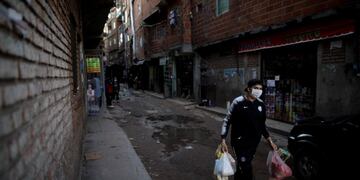 A man walks on a street after shopping during a government-ordered lockdown to curb the spread of the new coronavirus at a slum in Buenos Aires, Argentina, Sunday, April 26, 2020\u002E (AP Photo/Natacha Pisarenko)