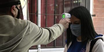 Workers at a high school check the temperature to a student before she enters to attend classes in Buenos Aires, Argentina, on October 13, 2020 amid the virus lockdown against the spread of the novel coronavirus, COVID-19 pandemic\u002E - The city government partially allowed students on their last year to attend face-to-face classes under a strict sanitary protocol and in the school open spaces\u002E (Photo by JUAN MABROMATA / AFP)