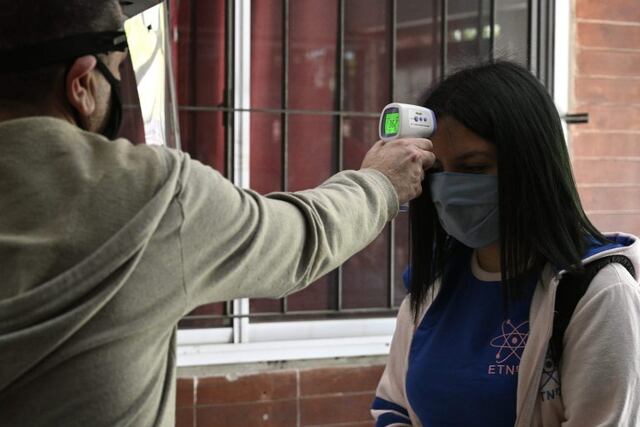Workers at a high school check the temperature to a student before she enters to attend classes in Buenos Aires, Argentina, on October 13, 2020 amid the virus lockdown against the spread of the novel coronavirus, COVID-19 pandemic\u002E - The city government partially allowed students on their last year to attend face-to-face classes under a strict sanitary protocol and in the school open spaces\u002E (Photo by JUAN MABROMATA / AFP)