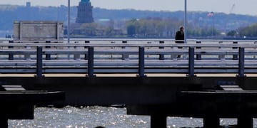 A man walks along Pier 34 while wearing a protective mask as they run along Hudson River Park Tuesday, May 12, 2020, in New York\u002E (AP Photo/Frank Franklin II)