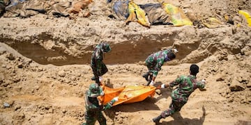 TOPSHOT - Indonesian soldiers bury quake victims in a mass grave in Poboya in Indonesia's Central Sulawesi on October 2, 2018, after an earthquake and tsunami hit the area on September 28\u002E - The Indonesian government on October 2 said the death toll from a devastating quake-tsunami on the island of Sulawesi had risen to 1,234 people, up from the previous count of 844\u002E (Photo by JEWEL SAMAD / AFP)