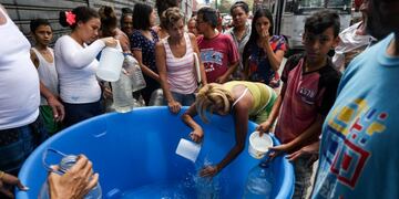 People fill cans with potable water in Caracas on March 10, 2019, during the third day of a massive power outage which has left Venezuelans without communications, electricity and water\u002E - The unprecedented power outage already left 15 patients dead and threatens to extend indefinitely, increasing distress for the severe political and economic crisis hitting the oil-rich South American nation\u002E (Photo by Cristian HERNANDEZ / AFP)