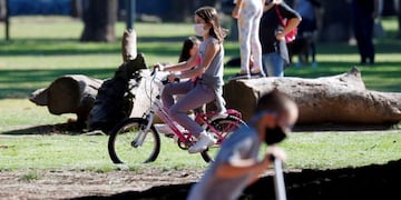 A girl wearing a face mask rides a bike in a park after restrictions were partially lifted for children in the city of Buenos Aires during the coronavirus disease (COVID-19) outbreak, Argentina May 16, 2020\u002E REUTERS/Agustin Marcarian
