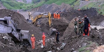 Los equipos de rescate buscan víctimas de un deslizamiento de tierra que enterró una mina de mineral de hierro en Xinyuan