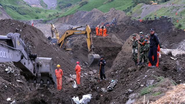 Los equipos de rescate buscan víctimas de un deslizamiento de tierra que enterró una mina de mineral de hierro en Xinyuan