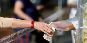 A woman pays in a shop protected with a tape as a preventive measure against the spread of the coronavirus disease (COVID-19) at a street market, in Buenos Aires, Argentina May 20, 2020\u002E REUTERS/Agustin Marcarian