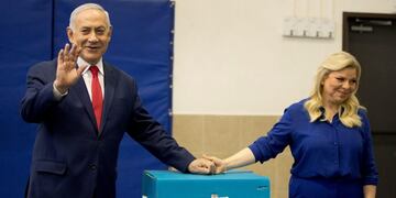 El primer ministro de Israel, Benjamin Netanyah, saluda junto a su mujer Sara, tras votar en las elecciones parlamentarias del país, en Jerusalén