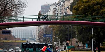 A man pushes a pram along a footbridge in Buenos Aires on July 18, 2020 a day after Argentina's government announced it was relaxing coronavirus containment measures in the capital to fight the COVID-19 pandemic\u002E - From Monday, non-essential businesses, industry and certain professional activities can restart and citizens will also be allowed to go outside for sport and to visit places of worship\u002E (Photo by Alejandro PAGNI / AFP)