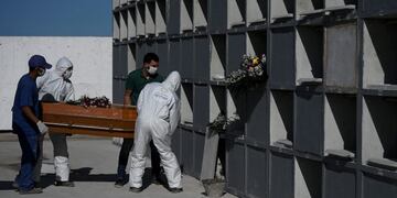 Cemetary workers wearing protective clothing place the coffin of a victim of the novel coronavirus, COVID-19, into a grave cubicle at Caju cemetary in Rio de Janeiro, Brazil, on May 9, 2020\u002E - The novel coronavirus has killed at least 276,435 people worldwide since the outbreak first emerged in China last December, according to a tally from official sources compiled by AFP at 1900 GMT on Saturday\u002E (Photo by Carl DE SOUZA / AFP)
