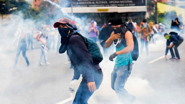 Venezuelan opposition activists clash with riot police during a protest against President Nicolas Maduro's government, in Caracas on April 13, 2017.nA 32-year-old man died Thursday after being shot and wounded in a demonstration on April 11, becoming the fifth victim in the protests that began almost two weeks ago. Dozens of people have been injured and more than 100 arrested since April 6, according to authorities. / AFP PHOTO / FEDERICO PARRA