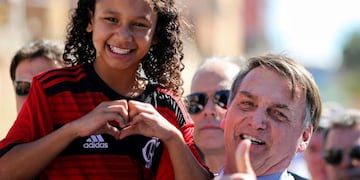 TOPSHOT - Brazilian President Jair Bolsonaro (R) poses with Yasmin Alves -who appeared in a video allegedly refusing to greet him, but already denied-, during a visit to her family house in the outskirts of Brasília, Brazil, on April 27, 2019\u002E - Bolsonrao had received Yasmin at the Planalto Palace earlier this week and presented her the Flamengo jersey she is wearing\u002E (Photo by Sergio LIMA / AFP)