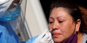 A healthcare worker takes a swab sample from a woman who had symptoms of the coronavirus disease (COVID-19), as part of the 'detectar' plan, in Villa Fiorito, on the outskirts of Buenos Aires, Argentina August 3, 2020\u002E REUTERS/Agustin Marcarian hispoado casos del dia test detectar en fiorito en provincia de buenos aires casa por casa coronavirus