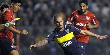 Boca Juniors' forward Dario Benedetto (C), between Independiente's defender Alan Franco (L) and midfielder Walter Erviti (R), kicks to score the team's third goal against Independiente during their Argentina first divsion football match at La Bombonera stadium in Buenos Aires, on June 4, 2017. / AFP PHOTO / ALEJANDRO PAGNI