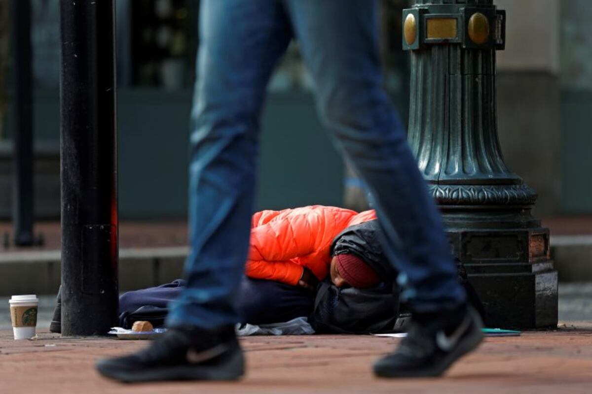 Cheyvonne Price, who says she is homeless primarily due to heroin addiction, naps on a sidewalk outside a Starbucks in downtown Portland, Ore\u002E, on Sept\u002E 20, 2017, after spending a night outside on the streets trying to keep dry in the rain\u002E Price said she hoped to get enough money during the day to afford a bed at a hostel for the night and said that she wishes people would realize that the homeless \