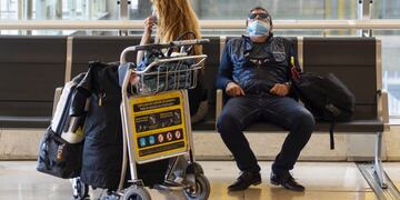 Passengers wear protective face masks as they sit on a bench in the departures terminal at Madrid Barajas airport, operated by Aena SA, in Madrid, Spain, on Sunday, March 15, 2020\u002E Spain declared a state of emergency effective immediately for 15 days, significantly limiting mobility in the country as the government seeks to stop the expansion of the novel coronavirus\u002E Photographer: Angel Navarrete/Bloomberg