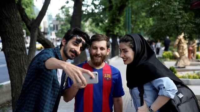 In this Monday, May 8, 2017 photo, two Iranians take a selfie with Reza Parastesh, Iranian doppelganger, or look-alike, of Lionel Messi, Argentinian soccer legend in Tehran, Iran. (AP Photo/Ebrahim Noroozi)