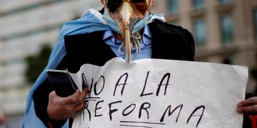 A man holds a poster with a message that reads in Spanish: \