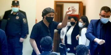 Former Brazilian soccer star Ronaldinho, seen through a pane of glass, waves during a court date at the Justice Palace in Asuncion, Paraguay, Monday, Aug\u002E 24, 2020\u002E Ronaldinho and his brother Roberto Assis have been detained since early March for allegedly entering the South American country with fake passports\u002E (AP Photo/Jorge Saenz)