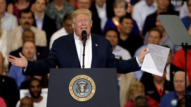 President Donald Trump gestures as he holds up a piece of paper on the presidential powers on immigration during a campaign rally Saturday, Feb. 18, 2017, at Orlando-Melbourne International Airport, in Melbourne, Fla. (AP Photo/Chris O'Meara)