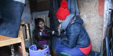 Lorena Henriques Sanches junto a funcionarios del Municipio acercando agua y leña