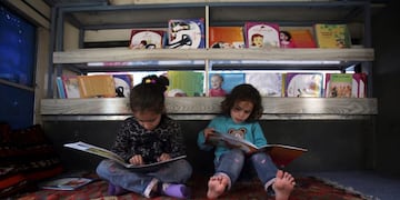 In this Saturday, March 10, 2018 photo, Afghan children read books inside a bus library, in Kabul, Afghanistan\u002E From sunrise to sunset, the bus drives around Kabul’s neighborhoods, stopping in each place for a couple of hours at a time\u002E The mobile library was the initiative of 25-year-old Freshta Karim who wanted to give Kabul’s children something badly missing in her own childhood -- the chance to widen one’s horizons, free of the shadow of war and poverty\u002E (AP Photo/Rahmat Gul) kabul afganistan Charmaghz micro azul que pone contentos a los chicos afganos biblioteca sobre ruedas recorre los barrios de la capital afgana el omnibus lleva libros para que los chicos niños puedan leer