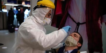 A health worker collects a nasal swab sample from a passenger to be tested for COVID-19 before he is allowed to board a ferry to Buenos Aires, at Argentinian ferry service company Buquebus' terminal in the port of Montevideo, on July 10, 2020\u002E - Technicians of the Technological Laboratory of Uruguay (LATU) set up a floating laboratory on a ferryboat of Buquebus -the only liner linking the capitals- after the polemic entry to Uruguay of two Argentinian citizens infected with COVID-19 in June\u002E The Uruguayan government of President Luis Lacalle Pou requires since Monday that travellers from abroad have a negative test for the new coronavirus done within 72 hours before the trip and another one seven days after, since flights from Europe were resumed\u002E (Photo by Pablo PORCIUNCULA / AFP)
