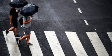 Men cross a street under the rain, in Buenos Aires, on January 29, 2020\u002E (Photo by RONALDO SCHEMIDT / AFP)