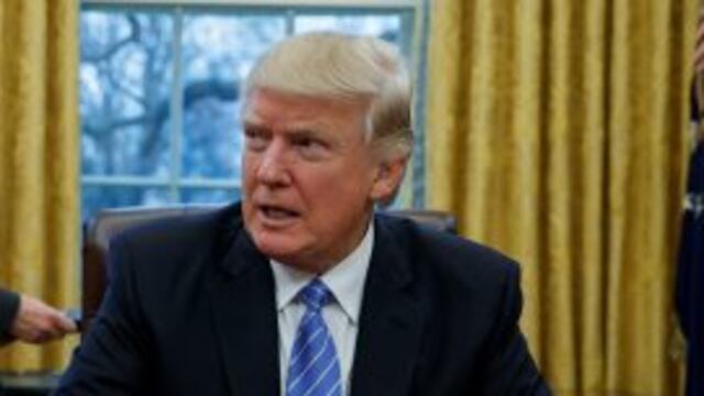 FILE - In this Jan. 23, 2017 file photo, President Donald Trump sits at his desk in the Oval Office of the White House in Washington. The legal fight over President Donald Trumpu2019s refugee ban is likely to turn on whether the president has the authority to