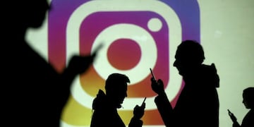 FILE PHOTO: Silhouettes of mobile users are seen next to a screen projection of Instagram logo in this picture illustration taken March 28, 2018\u002E REUTERS/Dado Ruvic/Illustration/File Photo