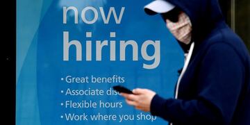 (FILES) In this file photo a man wearing a face mask walks past a sign \