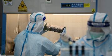 A lab technician wearing a protective suit, left, handles saliva samples for RT-PCR Covid-19 testing at Prenetics Ltd\u002E's laboratory in Hong Kong, China on Friday, July 31, 2020\u002E Prenetics, along with other Hong Kong labs and hospitals, has been overloaded with people seeking virus tests since the new wave emerged 18 days ago, Chief Executive Officer Danny Yeung said in an interview last month\u002E Photographer: Roy Liu/Bloomberg