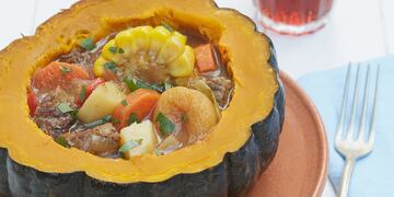 Carbonada en zapallo con vaso y tenedor