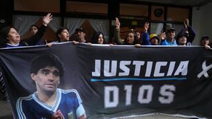 Seguidores del fallecido Diego Maradona sostienen una pancarta con la frase "Justicia para Dios" afuera del tribunal donde se realiza el juicio de homicidio por negligencia contra el personal médico que trató a Maradona, el martes 11 de marzo de 2025, en las afueras de Buenos Aires. (AP Foto/Natacha Pisarenko)