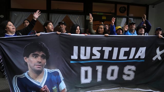 Seguidores del fallecido Diego Maradona sostienen una pancarta con la frase "Justicia para Dios" afuera del tribunal donde se realiza el juicio de homicidio por negligencia contra el personal médico que trató a Maradona, el martes 11 de marzo de 2025, en las afueras de Buenos Aires. (AP Foto/Natacha Pisarenko)