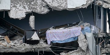 Una cama cuelga del edificio parcialmente destruido. (Foto: The Associated Press)