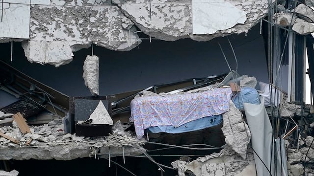 Una cama cuelga del edificio parcialmente destruido. (Foto: The Associated Press)